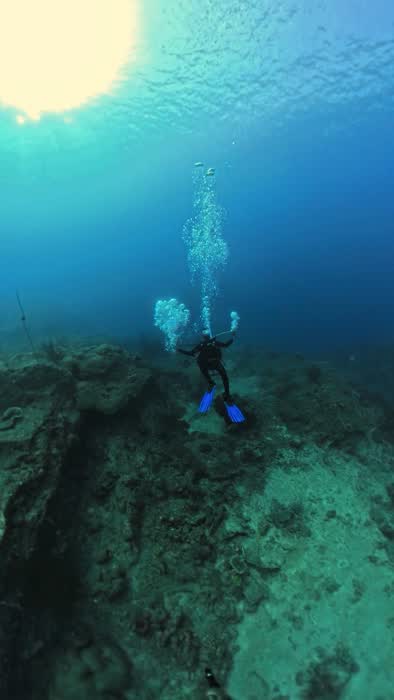 A diver descending with the sun burning through the surface above