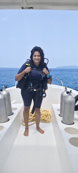 A diver in full scuba gear giving a thumbs up on the boat