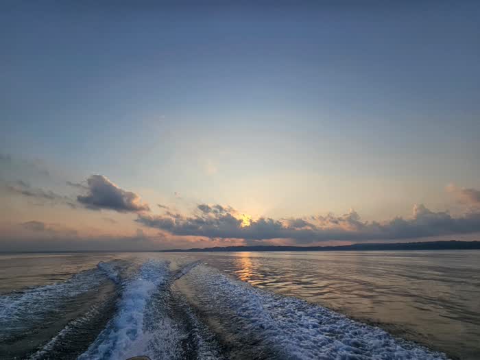 The wake of the dive boat heading home under a sunset sky
