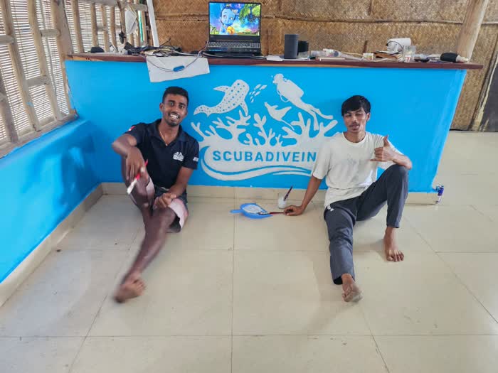 Two members of staff sitting in front of the painted ScubaDiveIn counter