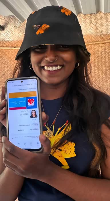 A diver smiling and holding up a phone showing a new certification card